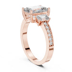 Rose-gold plated Silver ring with three emerald-cut center stones and smaller round stones on a white background 