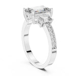 Silver ring with three emerald-cut center stones and smaller round stones on a white background 