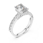 Silver ring with a central emerald-cut diamond and smaller diamonds on a white background 