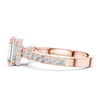 Rose-gold plated Silver ring with a central emerald-cut diamond and smaller diamonds on a white background 